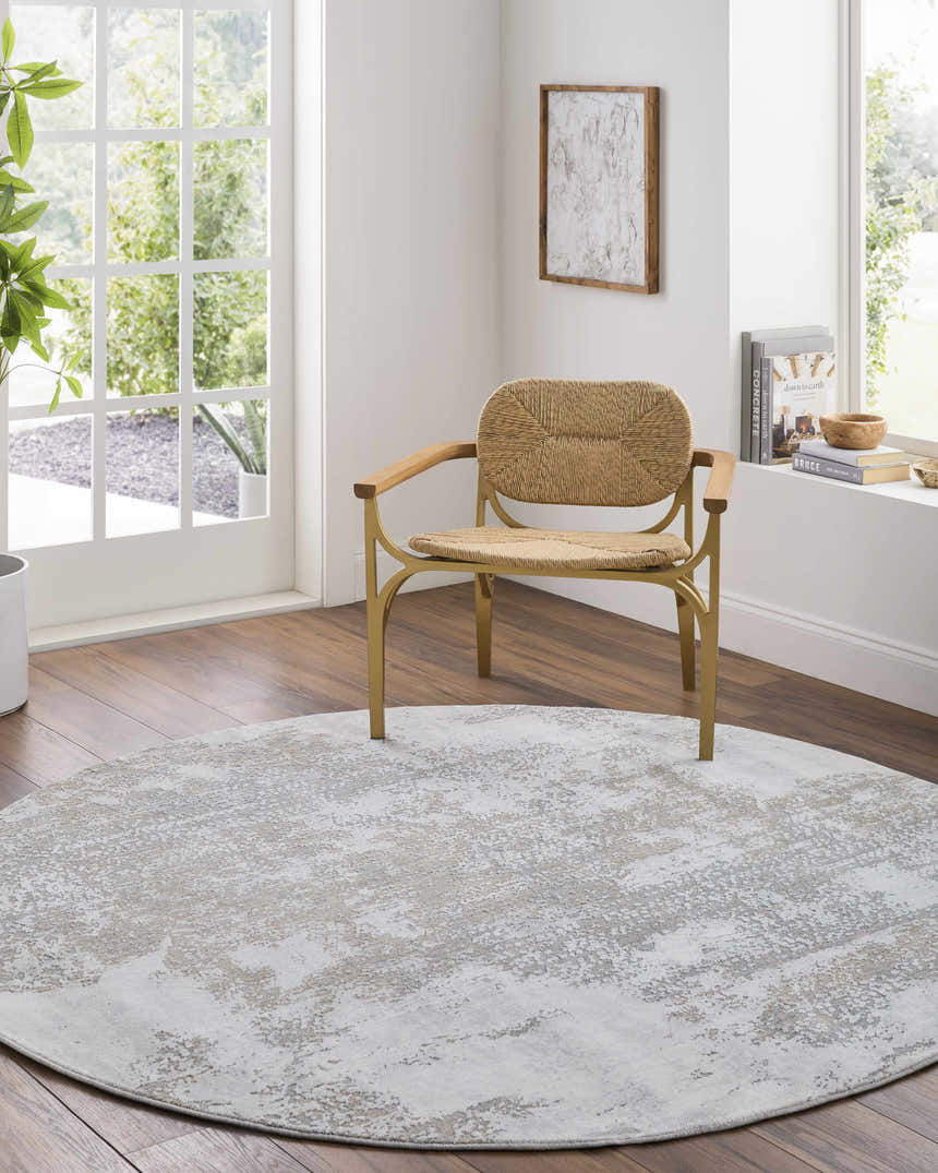 Sunlit room scene with a round Adwoa Boutique Rug in gray and brown tones under a woven chair. Roomscene-Round
