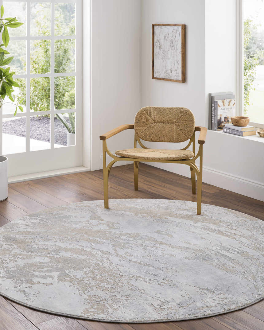 Light-filled living room with a round Ambra Thick Luxe Boutique Rug in cloud gray and beige under a woven chair. Roomscene-Round