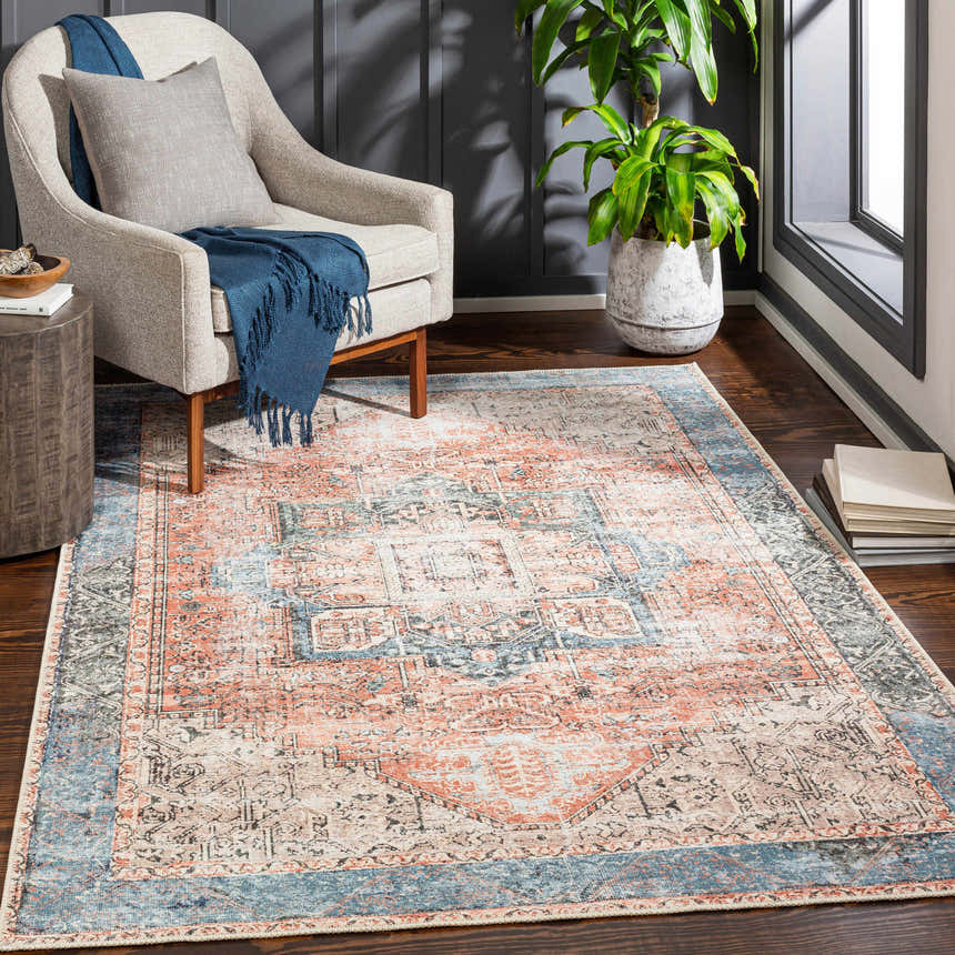 Living room scene with Livabliss Amelie AML-2309 rug in beige, pink, and blue. Armchair, plant, and wood floors complete the look. Roomscene-Rectangle