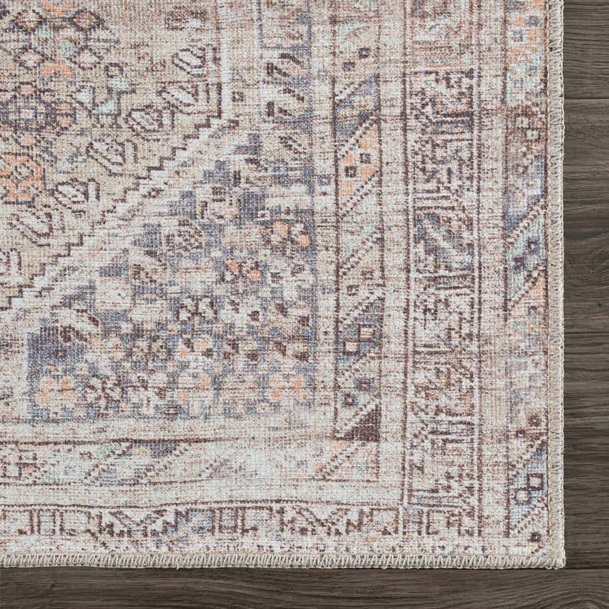 Close-up of the Barny Tan Washable Area Rug, showcasing its traditional design, tan, gray, and peach hues, and woven texture. Corner