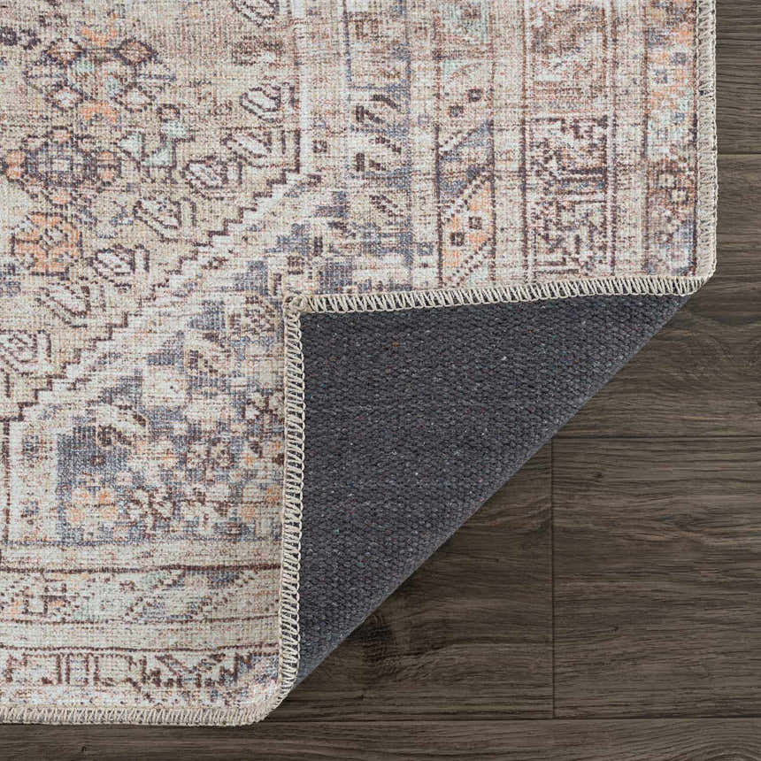 Close-up of the Barny Tan Washable Area Rug showing its traditional design, tan color wash, and gray backing. Fold