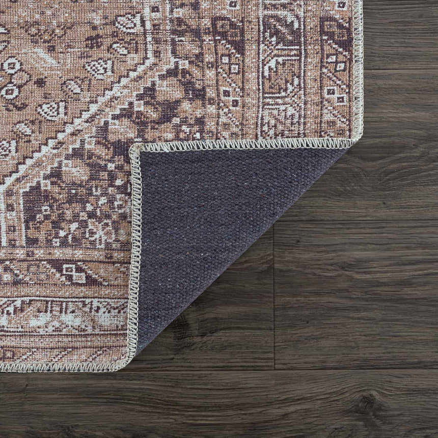 Close up of the Barny Brown washable rug showing its traditional pattern, brown tones, and gray backing. Fold