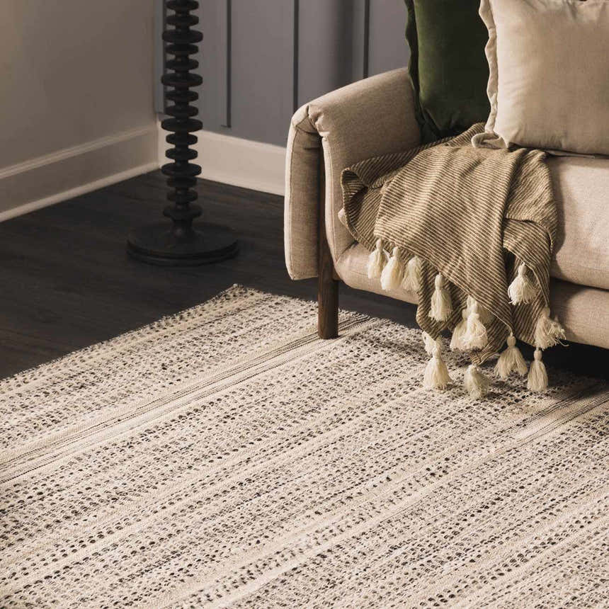 Living room scene with a beige sofa and the Arabi Wool Area Rug in light beige and black. Roomscene-Rectangle