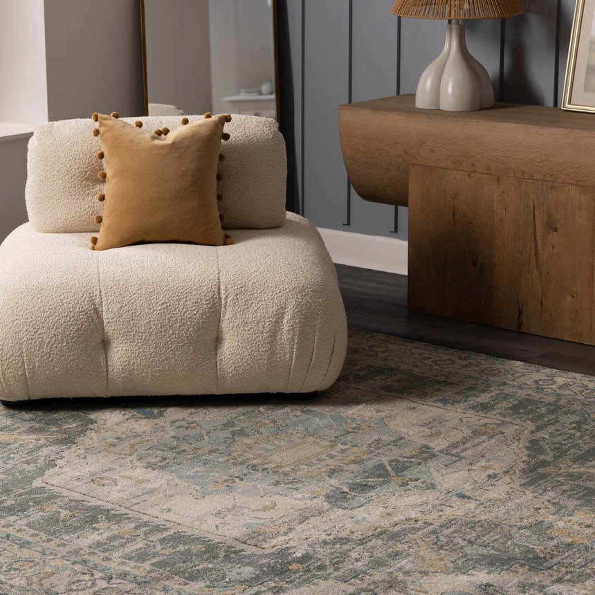 Living room scene with a beige chair on the Vaeda Blue Thick Luxe Rug. The rug has beige, gray, and blue tones. Styleshot