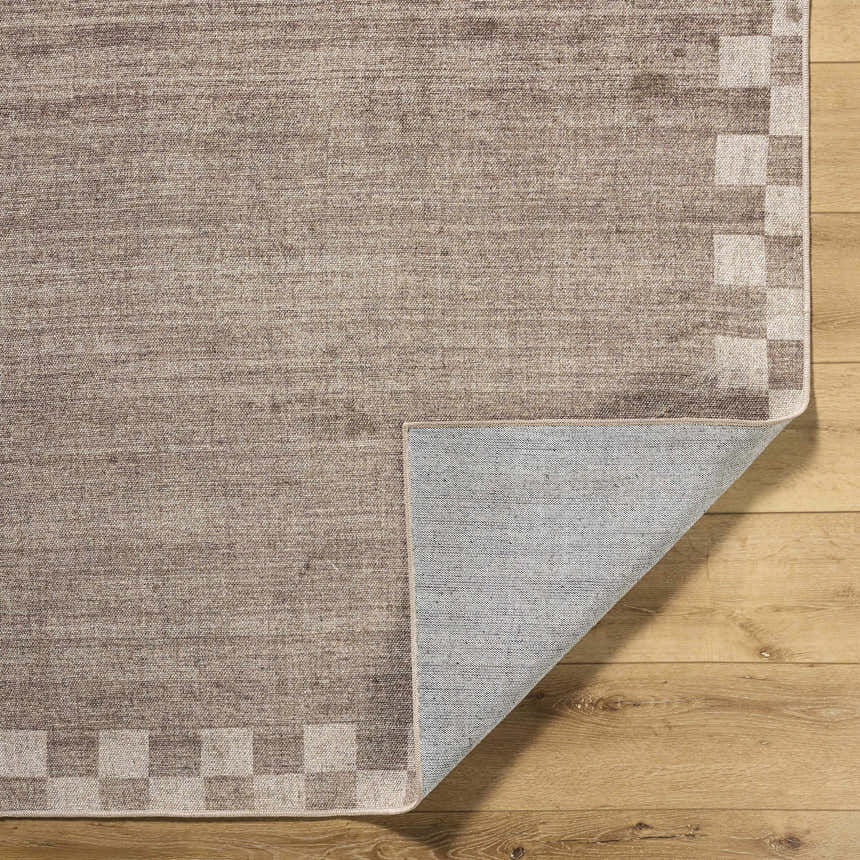 Close-up of the Bardot Washable Area Rug showing its brown woven texture, checkerboard border, and non-slip backing. Fold