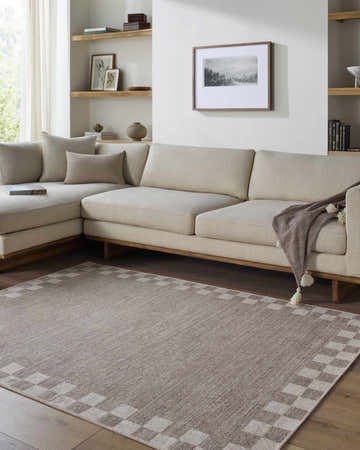 Living room with neutral sectional and Bardot Washable Area Rug. The rug has a checkerboard border and complements the warm tones. Roomscene-Rectangle
