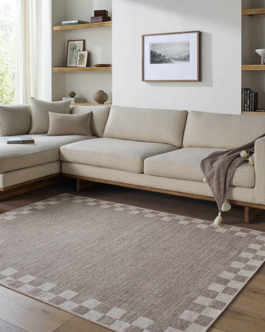 Living room with neutral sectional and Bardot Washable Area Rug. The rug has a checkerboard border and complements the warm tones. Roomscene-Rectangle