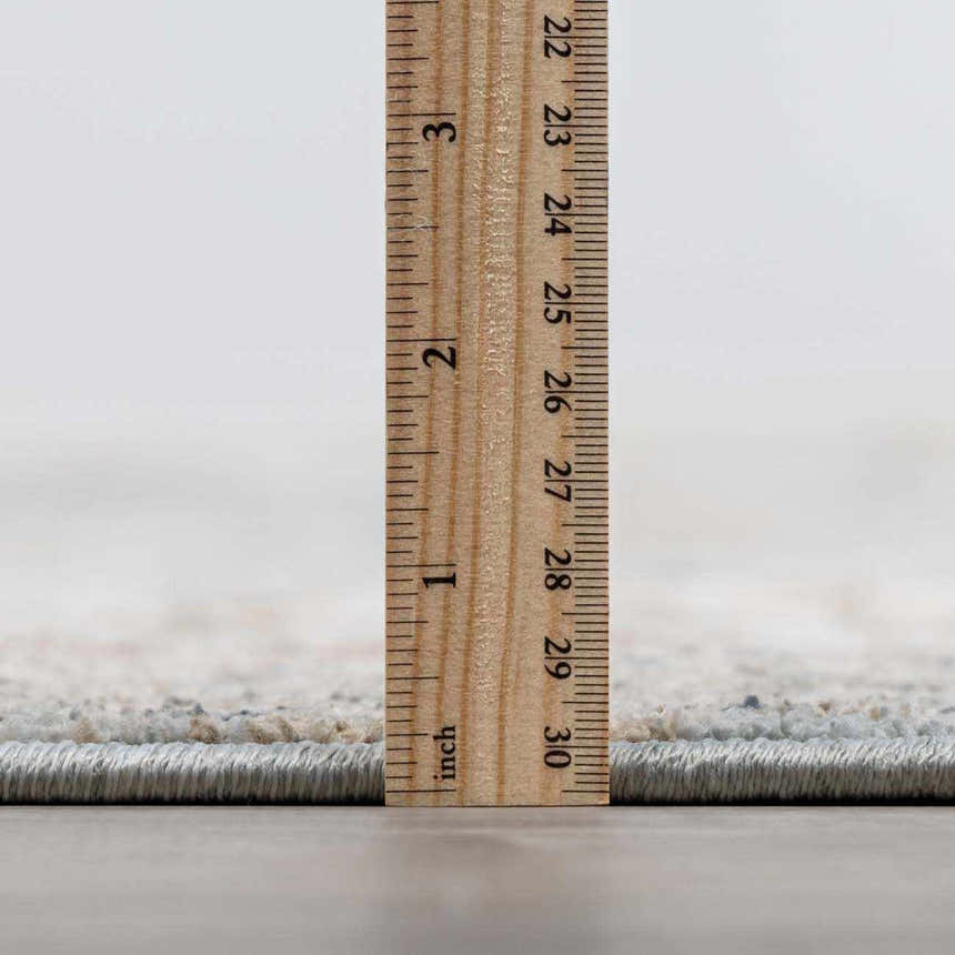 Close-up of Kouta Gray Blue Area Rug pile height, showing texture and rug thickness with a ruler. Pile