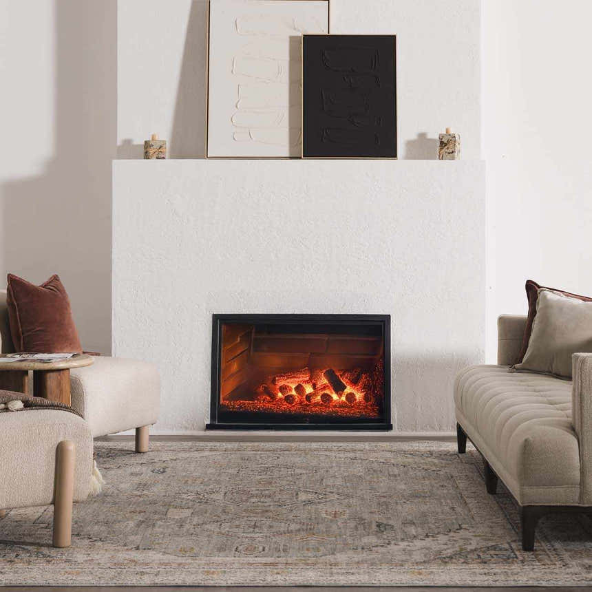 Living room scene with fireplace and beige seating featuring the Kouta Gray Blue Area Rug. Roomscene-Rectangle