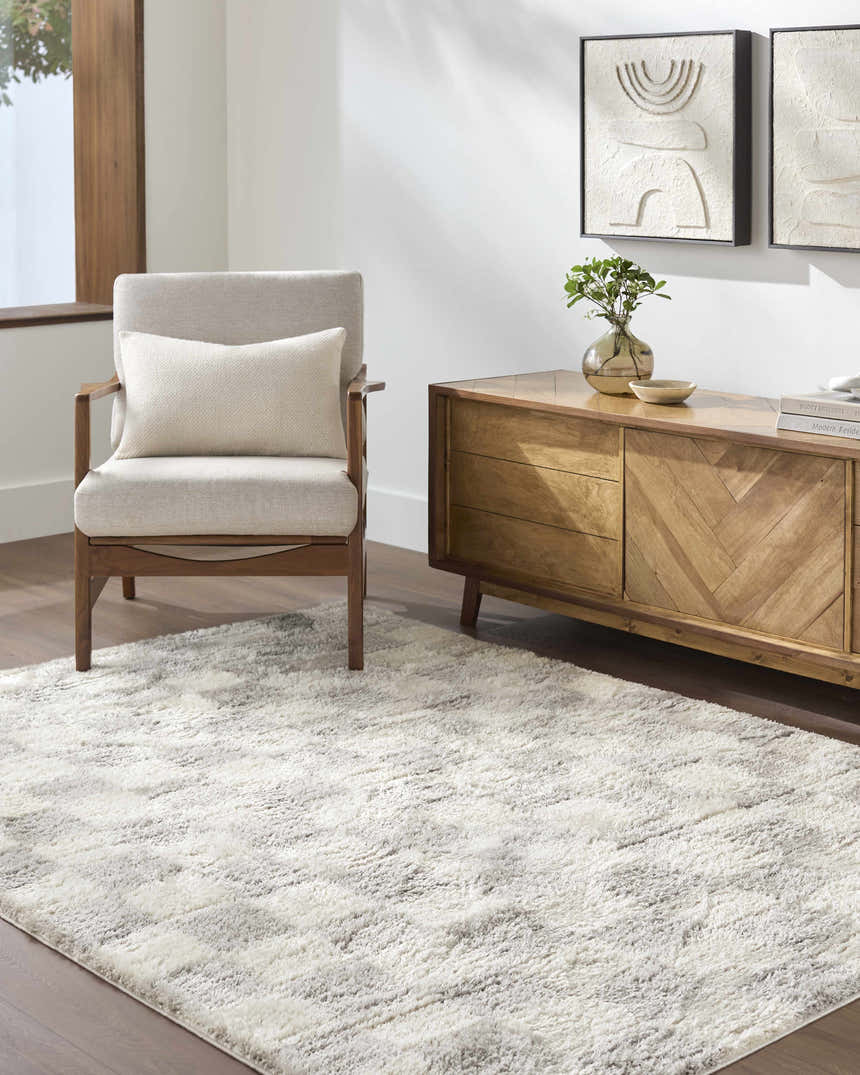 Living room scene with a Belita Tan Luxe Shag Area Rug, light wood furniture, neutral chair, and modern art. Roomscene-Rectangle