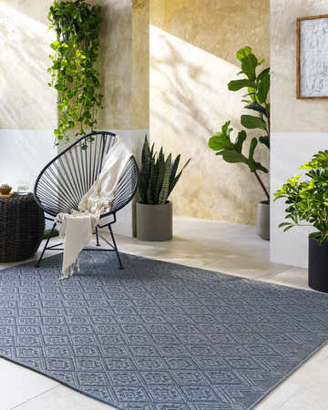 Sunlit patio with a gray Bandit Area Rug, black chair, and potted plants creating a relaxing, modern farmhouse vibe. Roomscene-Rectangle
