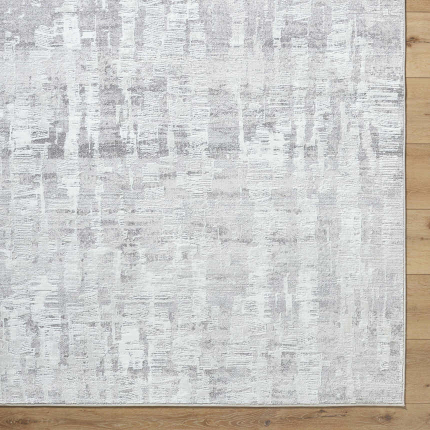 Close-up of the Branka Area Rug. Light silver, silver gray, and slate blue contemporary design. Machine woven texture. Corner