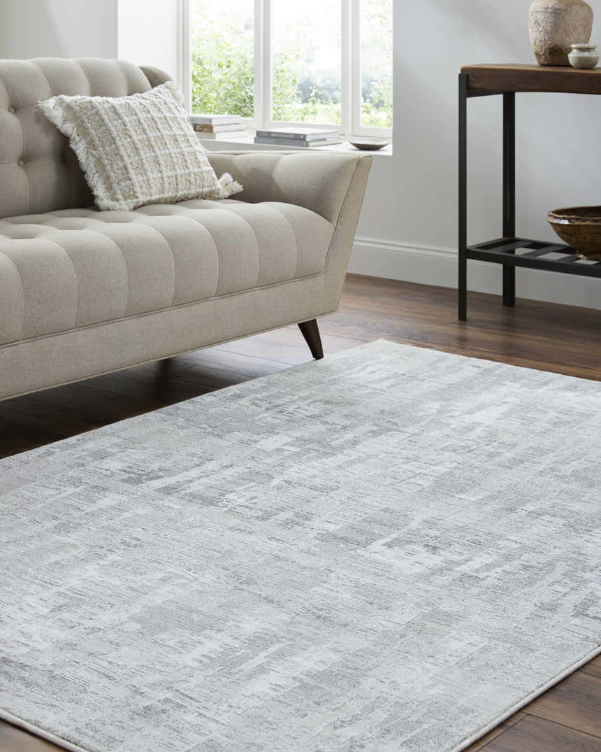 Living room scene with a light silver Branka Area Rug, beige sofa, and dark wood floors. Roomscene-Rectangle