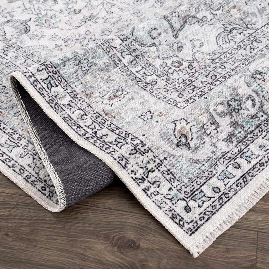 Close-up of the Light Blue Holi-4603 Washable Area Rug, featuring a traditional vintage pattern and charcoal, blue, and gray tones. Fold
