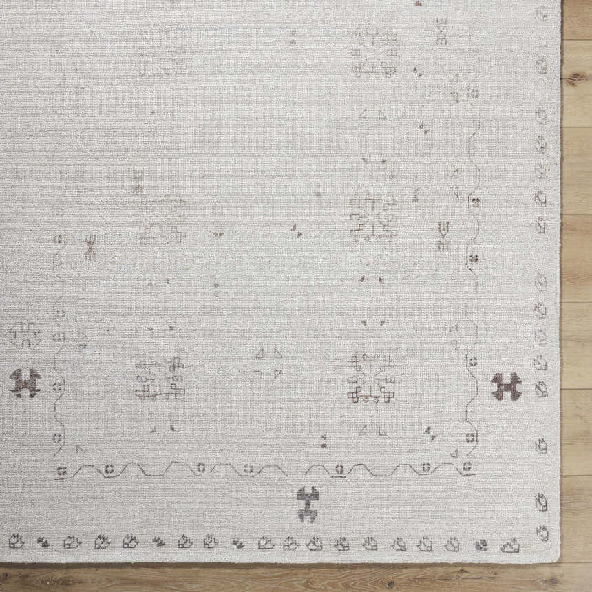 Close up of the ivory Bhavna Area Rug showing the hand tufted texture and sandstone geometric pattern. Corner