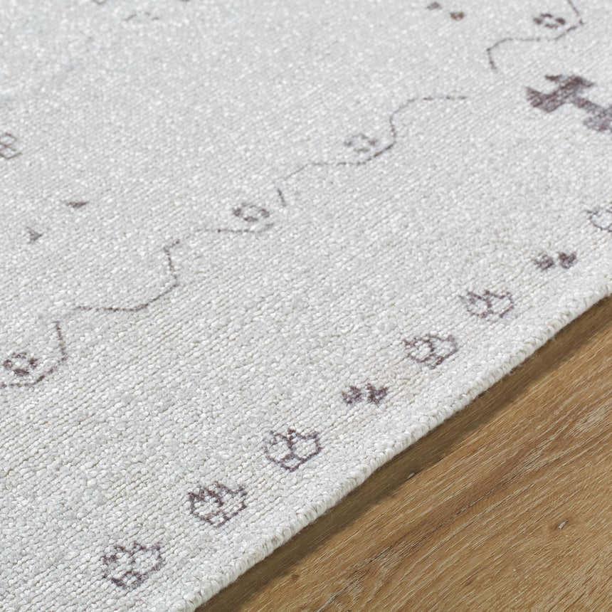 Close-up of the hand-tufted Bhavna Area Rug. Ivory rug with a subtle sandstone and taupe traditional pattern. Texture