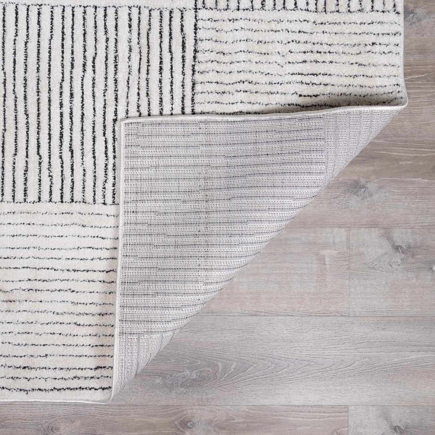 Close-up of the Modern Scandi Architect I Area Rug. Ivory rug with black stripes and geometric pattern. Machine woven polyester. Fold