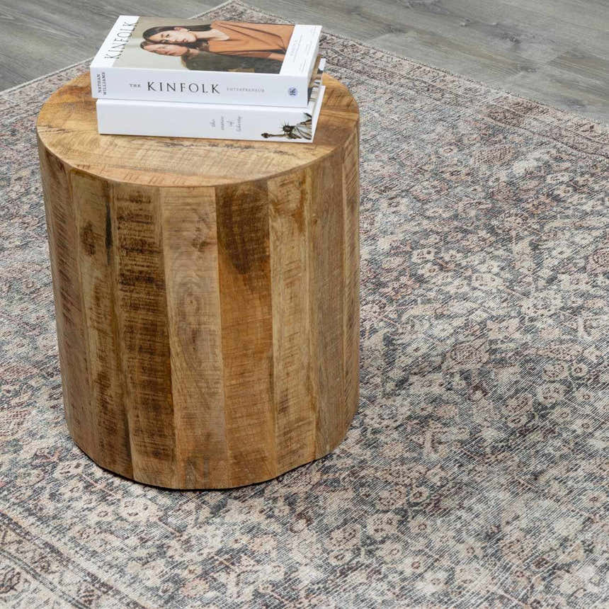 Close-up of a Collins Avenue III Vintage Damask Area Rug with beige, red, and green tones under a wood side table with books. Styleshot