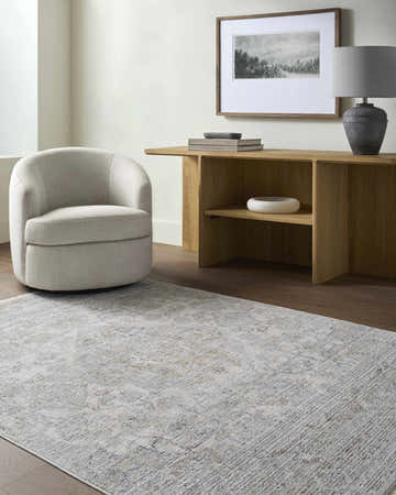Living room scene with a Bimala Area Rug in light gray, cream, and tan, paired with a cream swivel chair and wood console table. Roomscene-Rectangle