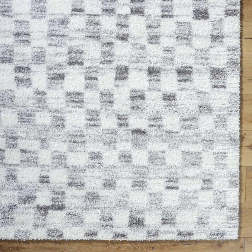 Close up of the Aneska Area Rug. Shag rug with a contemporary gray and ivory checkerboard pattern. Corner