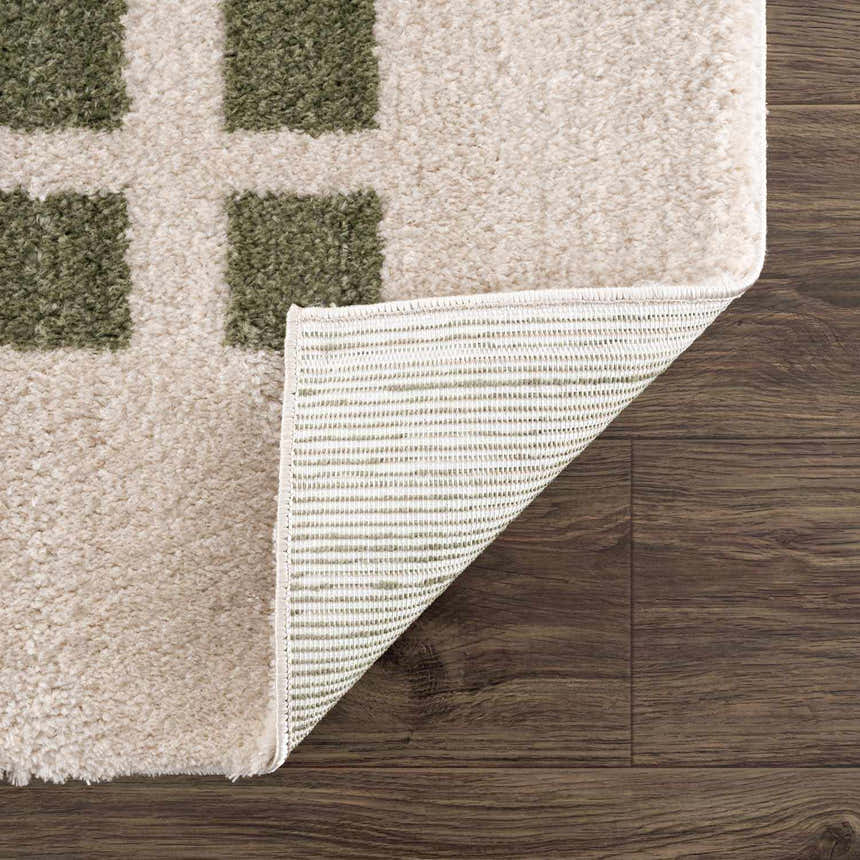 Close-up of the Baback Green Washable Area Rug showing lime green squares on a cream background and the rug's backing. Fold