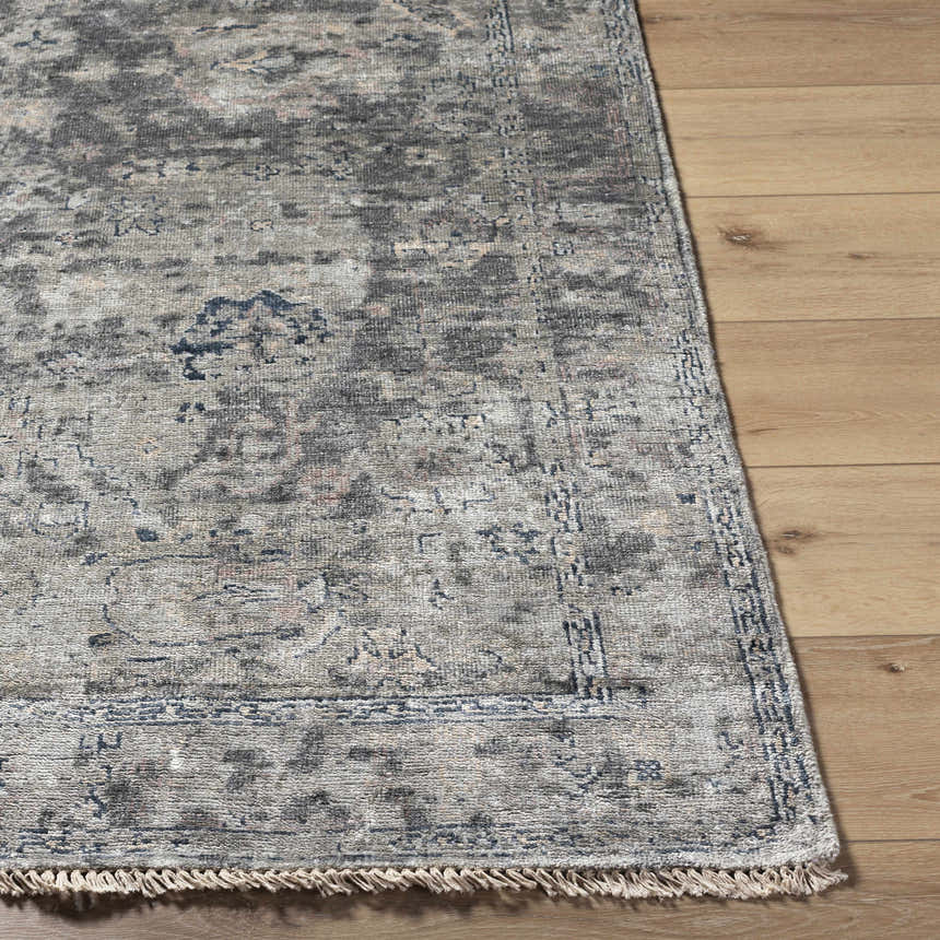 Close up of the Ballantrae Premium Rug showing its beige, charcoal, and blue traditional pattern and fringe. Front