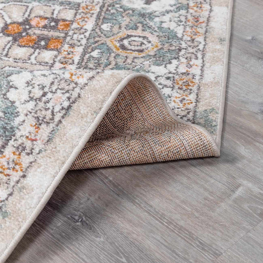 Close-up of the Bolinas Area Rug showing its traditional pattern, brick red, camel, and sky blue colors, and machine-woven construction. Fold