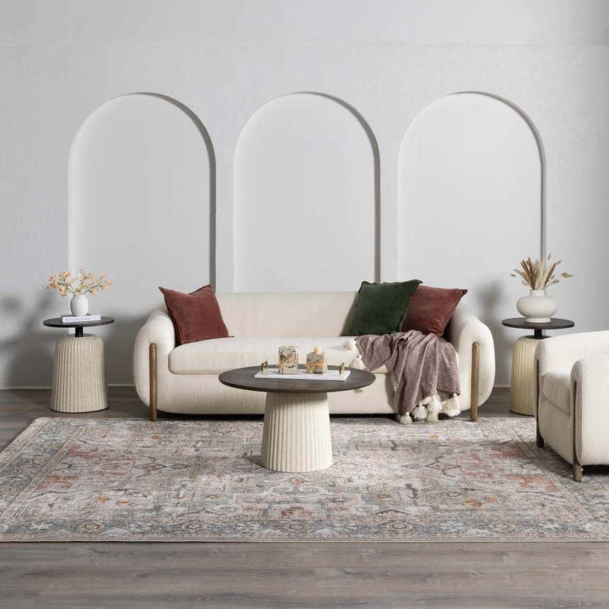 Living room scene with a Bolinas area rug, cream sofa, and neutral decor. The rug features brick red, camel, and gray tones. Roomscene-Rectangle