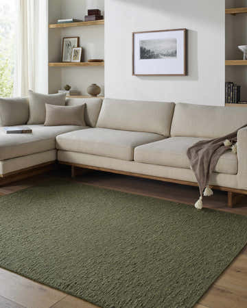 Living room scene with a Breena Olive Washable Area Rug, a beige sectional sofa, and light wood accents. Roomscene-Rectangle