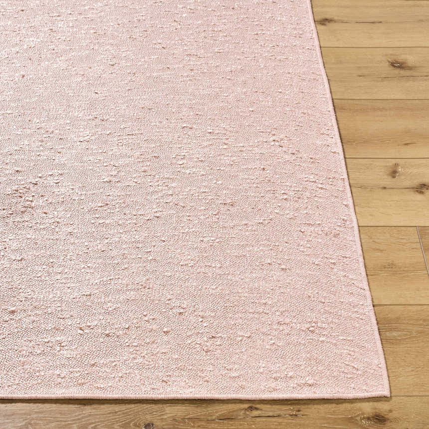 Close-up of the hand-woven Breena Blush Washable Area Rug showing texture and blush color on wood floor. Front