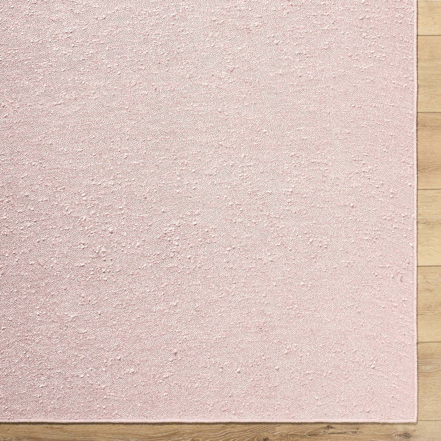 Close-up of the Breena Blush Washable Area Rug showing the texture and blush color on a wood floor. Corner