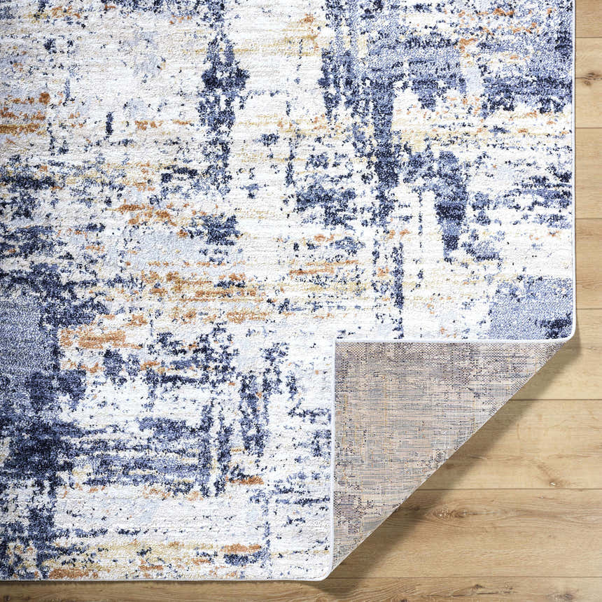 Close-up of Bazyli Area Rug showing ivory, light gray, navy, and peach contemporary design and machine woven construction. Fold