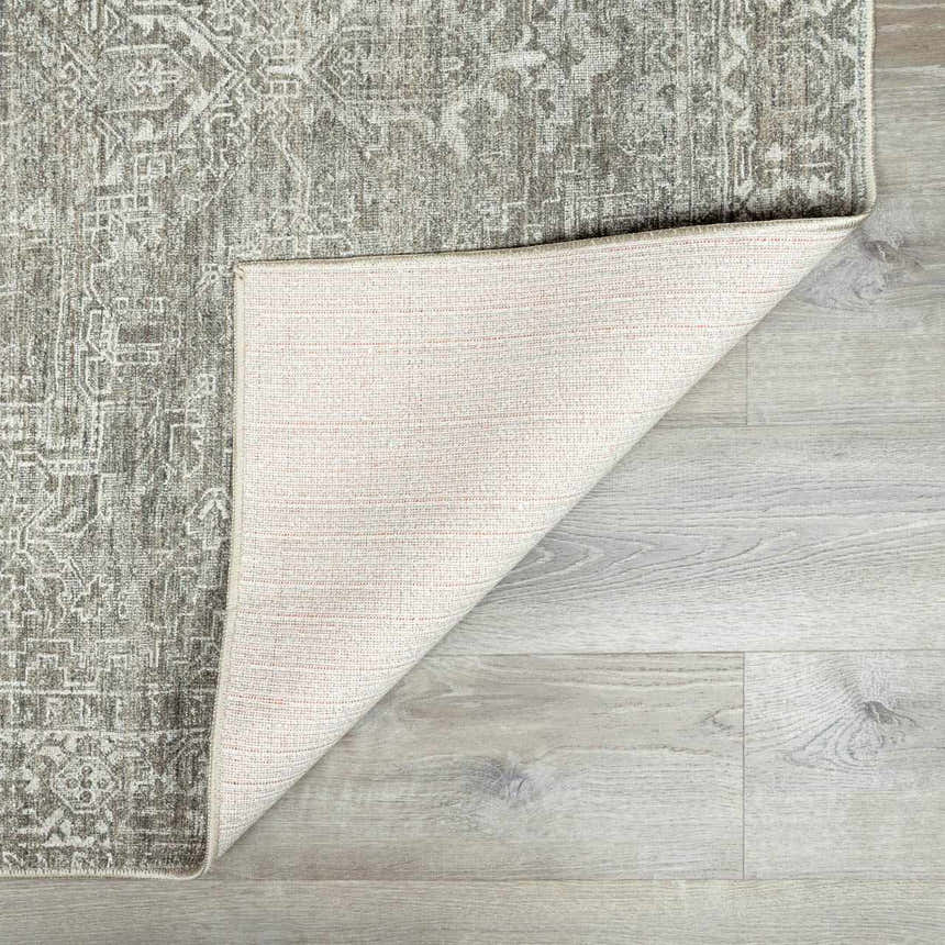 Close-up of the Galey Alix Collins Avenue VII Vintage Medallion Rug showing its gray, green, and ivory pattern and backing. Fold