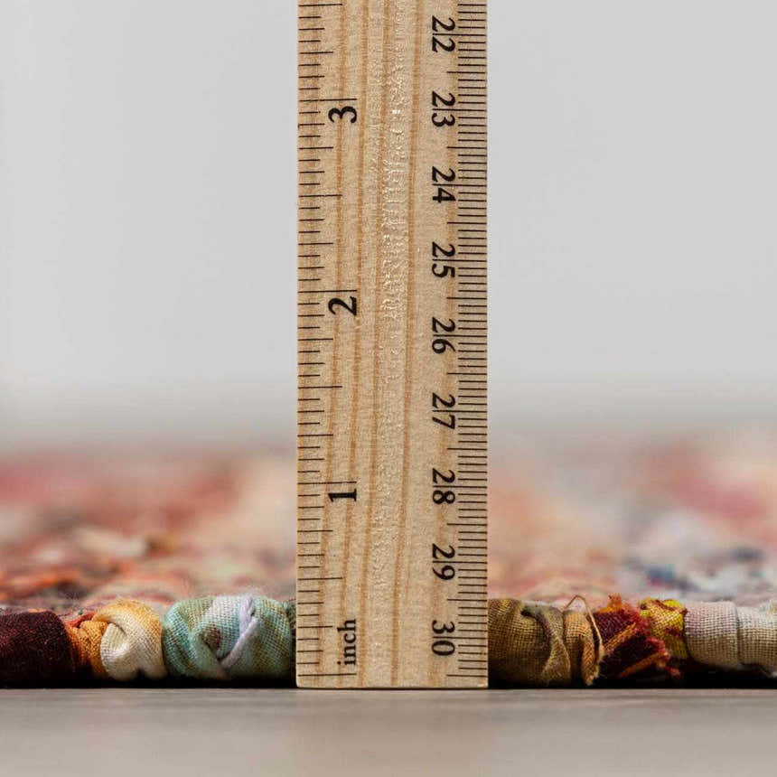 Close-up of the Brenda Crimson Area Rug showing the rug's thickness with a ruler. Pile