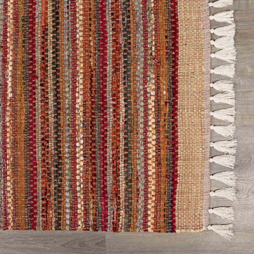 Close-up of the hand woven Brenda Crimson Area Rug. Features stripes of red, orange, and green, and white tassels. Swatch