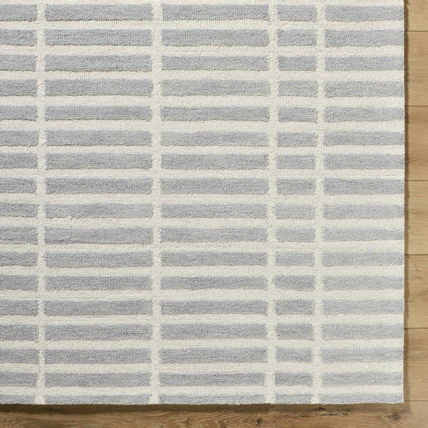 Close-up of the Bendek Medium Gray Area Rug showing its ivory and gray horizontal block pattern and hand-tufted wool texture. Corner