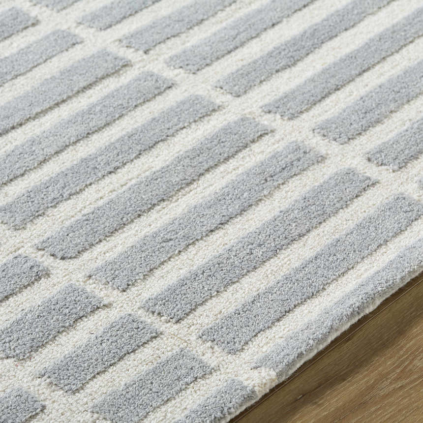 Close-up of the hand-tufted Bendek Medium Gray Area Rug. Ivory and gray wool rug with a contemporary geometric pattern. Texture
