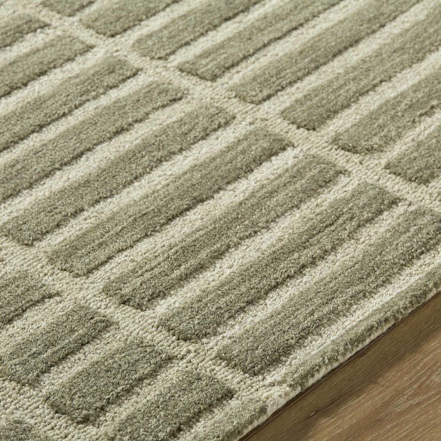 Close up of the hand tufted Bendek Olive Area Rug, featuring a beige and sage geometric pattern. Texture
