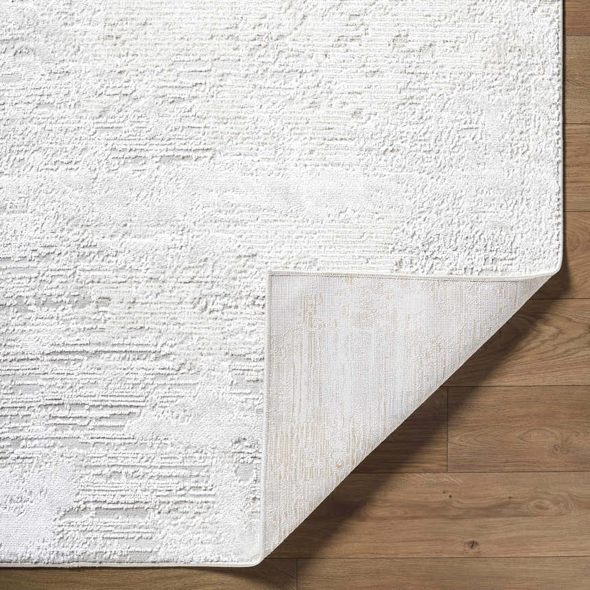 Close-up of the Aramis Area Rug showing its cream, ivory, and light gray textured design on wood flooring. Fold