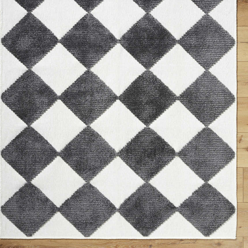Close-up of the Bosley Black Washable Area Rug. Features a black and off-white diamond pattern with a textured pile. Corner