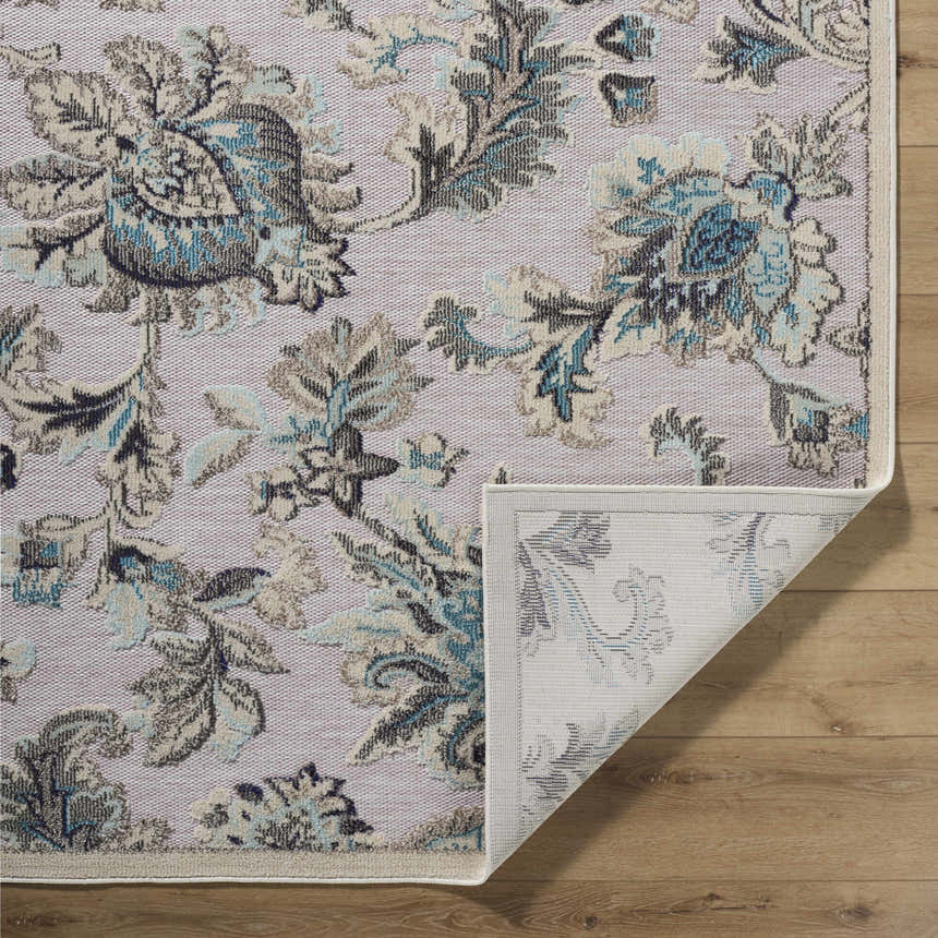 Close-up of the Benita Area Rug. Aqua, cream, and light brown floral pattern on a tan background. Machine woven texture. Fold