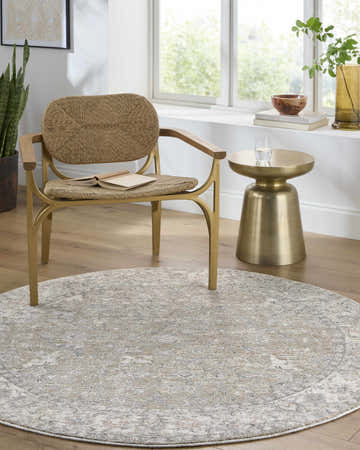Cozy reading nook with a round Brynja Cream Area Rug, woven chair, gold side table, and natural light. Roomscene-Round