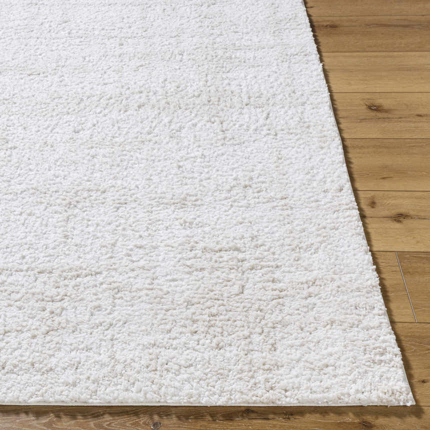 Close up of the white, plush texture of the Bianca Area Rug on hardwood flooring. Front
