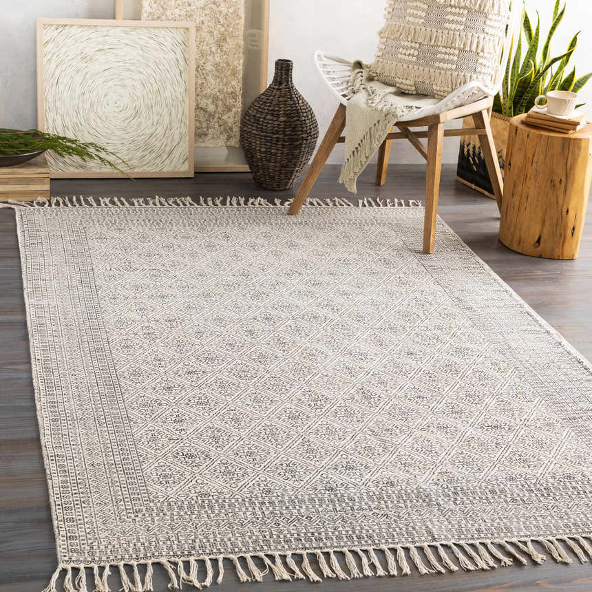 Living room scene with a beige and black Brushton Area Rug, chair, and natural decor. Roomscene-Rectangle