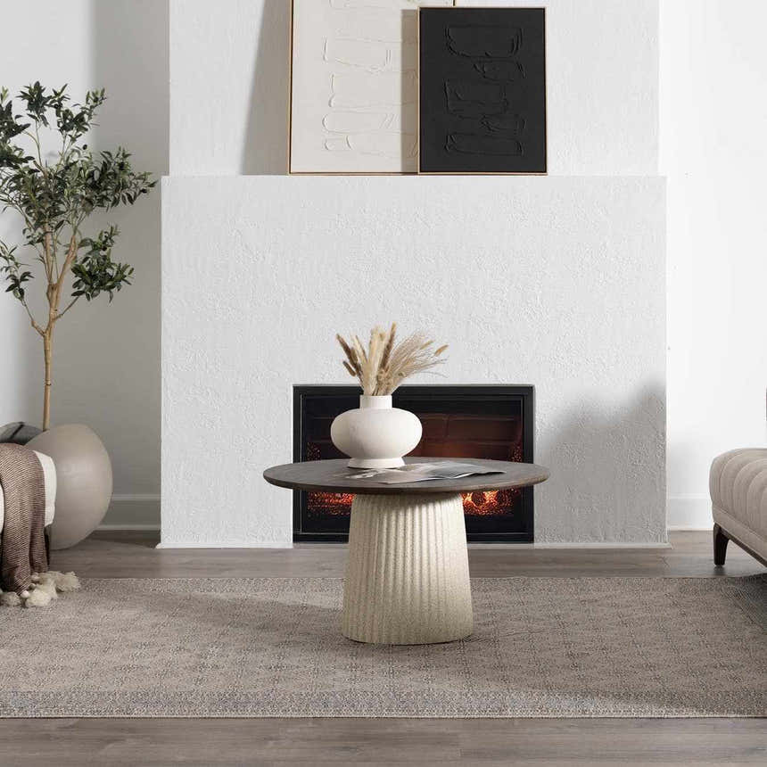 Living room scene with a beige Brushton Area Rug, fireplace, round table, and neutral decor. Roomscene-Rectangle