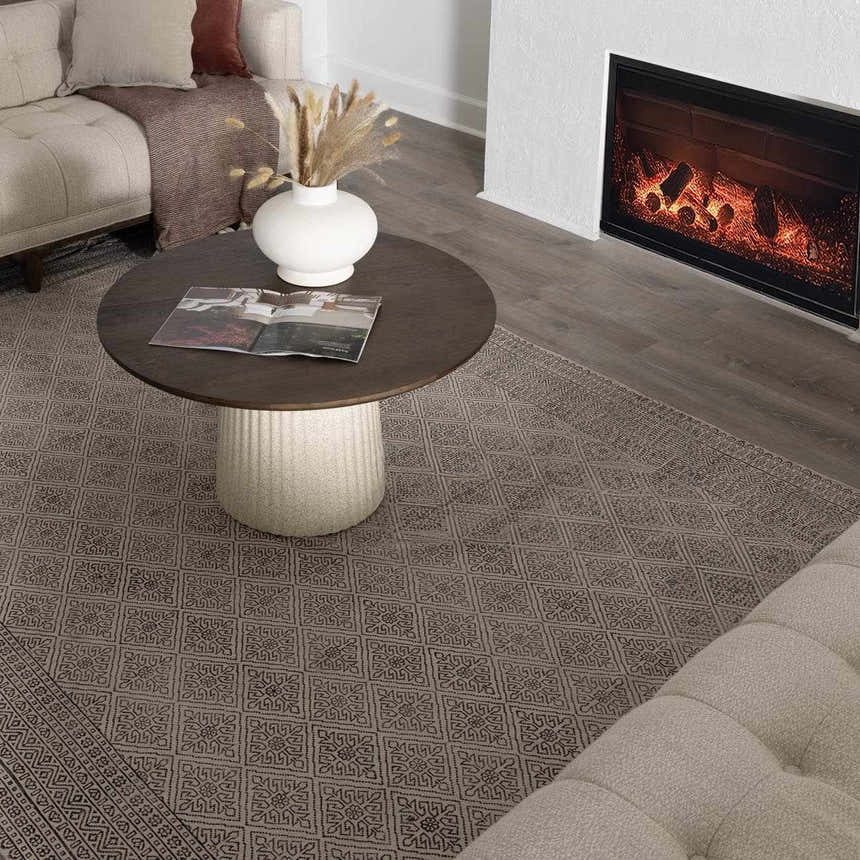 Living room scene with a beige Brushton Area Rug, sofa, round coffee table, and fireplace. Roomscene-Rectangle