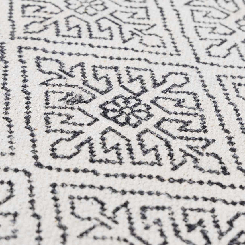 Close-up of the Brushton Area Rug showing its hand-woven texture and geometric black and beige pattern. Texture