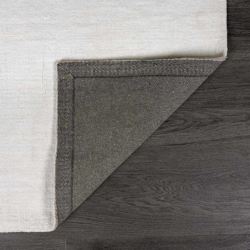 Close-up of the white Brownsdale Area Rug showing the hand-loomed texture and backing. Fold