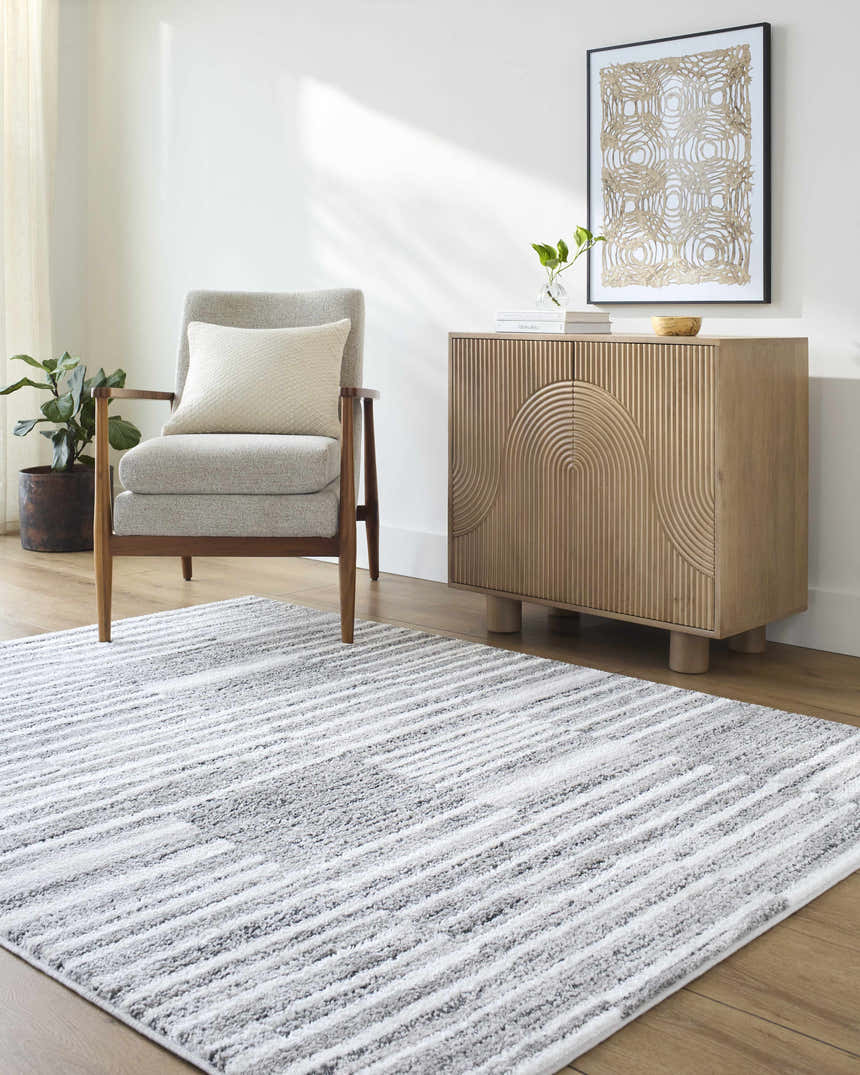Living room scene with gray armchair and Bashar Area Rug in black, ivory and gray stripes. Roomscene-Rectangle