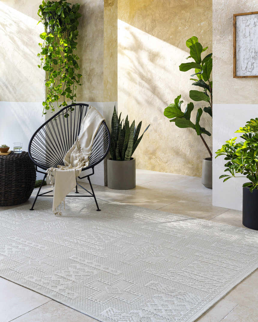 Sunlit patio scene with a light silver Branko Area Rug, modern chair, and lush potted plants. Roomscene-Rectangle